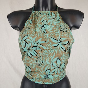 Puede incluir: Un top halter con estampado floral marrón y turquesa. El top está hecho de una tela suave y ligera y tiene un ajuste holgado.