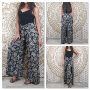 Op de afbeelding: Wijde broek met een bloemenprint in tinten blauw en goud. De broek heeft een strik in de taille en is gemaakt van een zachte, vloeiende stof.