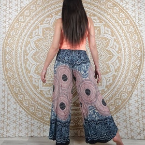 Puede incluir: Pantalones de pierna ancha con un estampado circular rosa y azul marino. Los pantalones tienen un borde decorativo y se combinan con una camiseta sin mangas color melocot&oacute;n. El fondo presenta un tapiz de mandala dorado.