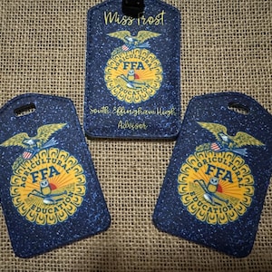 May include: Three blue and yellow fabric keychains with the FFA logo and the text "Agricultural Education" and "FFA". The keychain on the top has the text "Miss Frost South Effingham High Advisor".