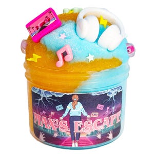 May include: A jar of colorful slime with a decorative top. The top features a pink cassette tape, white headphones, and musical notes. The jar has a label with the text "MAX'S ESCAPE" and a graphic of a person.