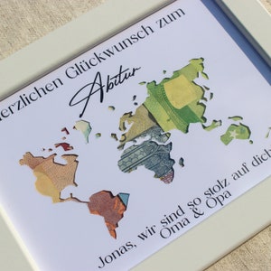 May include: A white framed card with a world map cut out of it. The map is filled with different currency bills. The card has the text "Herzlichen Gl&uuml;ckwunsch zum Abitur" and "Jonas, wir sind so stolz auf dich Oma & Opa".