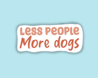 May include: A white sticker with a pink and orange gradient text that reads "Less people More dogs".