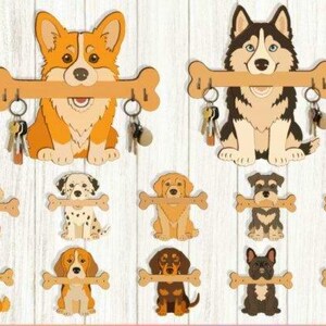 Peut inclure: Une collection de porte-clés muraux en bois en forme de diverses races de chiens, chacun tenant une barre horizontale en forme d'os avec des crochets métalliques. Les chiens présentent des illustrations détaillées de races variées.