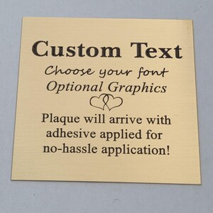 Puede incluir: Placa cuadrada dorada con texto negro. El texto dice "Custom Text", "Choose your font", "Optional Graphics" y "Plaque will arrive with adhesive applied for no-hassle application!"