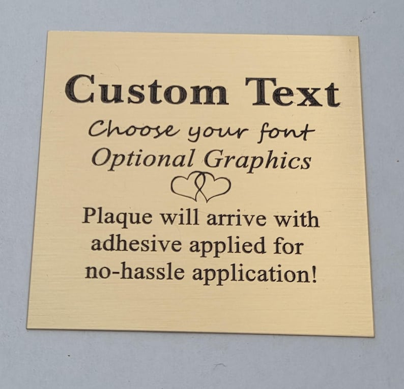 Puede incluir: Placa cuadrada dorada con texto negro. El texto dice "Custom Text", "Choose your font", "Optional Graphics" y "Plaque will arrive with adhesive applied for no-hassle application!"