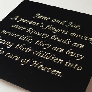 Puede incluir: Placa cuadrada negra con texto grabado en fuente cursiva. El texto dice: "Jane and Joe, A parent's fingers moving over Rosary beads are never idle; they are busy cing their children into e care of Heaven."