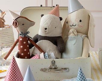 May include: A white vintage suitcase with a brown and white fox, a panda bear, and a white bunny wearing party hats. The suitcase is surrounded by colorful party hats.