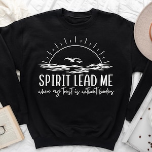 May include: Black sweatshirt with a white graphic design of a sun setting over the ocean with birds flying. The text "SPIRIT LEAD ME where my trust is without borders" is printed below the graphic.