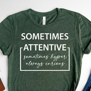 May include: Forest green t-shirt with the text "SOMETIMES ATTENTIVE sometimes hyper always curious" in white.