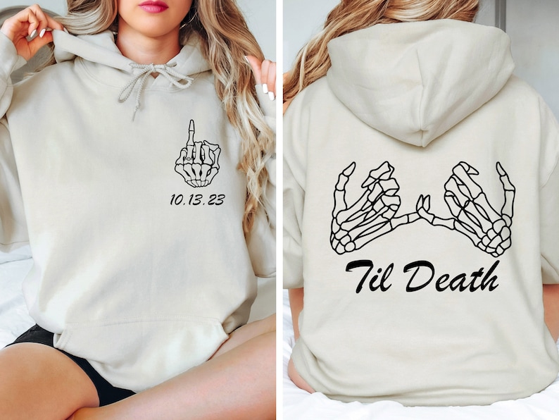 May include: Cream-colored hoodie with black skeleton hand graphics. The front features a hand giving the middle finger and the date "10.13.23". The back displays two skeleton hands forming a promise with the text "Til Death".