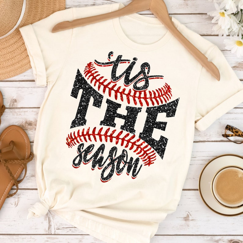 May include: A white t-shirt featuring a black and red baseball graphic with the text "'tis the season" in black glitter.