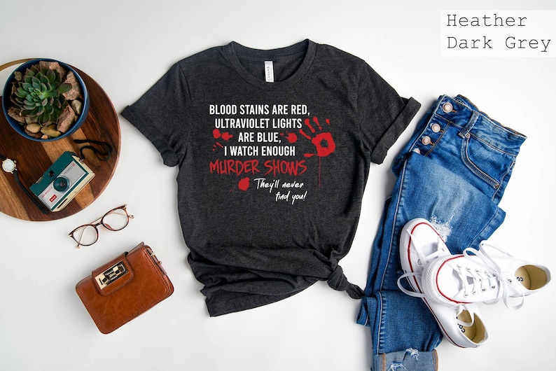May include: Heather dark grey t-shirt with a red bloody handprint and the text "BLOOD STAINS ARE RED, ULTRAVIOLET LIGHTS ARE BLUE, I WATCH ENOUGH MURDER SHOWS They'll never find you!"