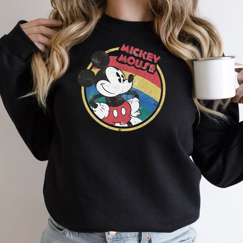 Puede incluir: Sudadera negra con un gr&aacute;fico de estilo vintage de Mickey Mouse en un c&iacute;rculo con un arco&iacute;ris y el texto "Mickey Mouse".