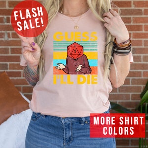 May include: A pink t-shirt with a vintage-style graphic of a person with a dice for a head. The graphic says "Guess I'll Die".
