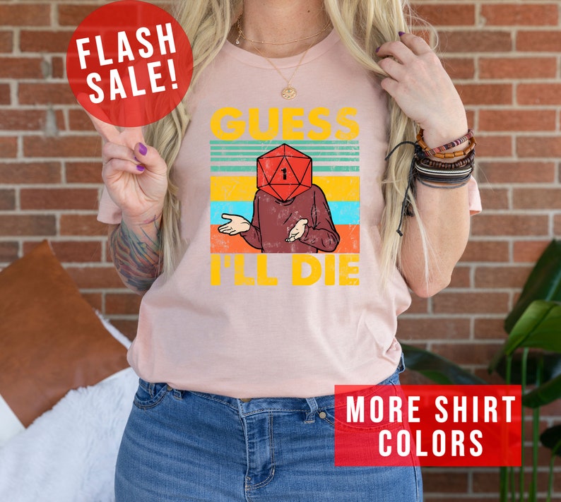 May include: A pink t-shirt with a vintage-style graphic of a person with a dice for a head. The graphic says "Guess I'll Die".