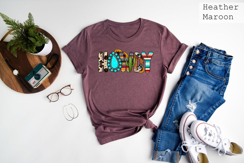 May include: A heather maroon t-shirt with the word "HORDY" printed in colorful letters. The letters are decorated with various patterns, including turquoise, sunflowers, cacti, and animal print.