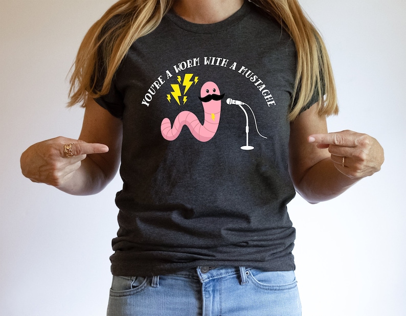 May include: A dark gray t-shirt with the text "You're a worm with a mustache" in white. The graphic features a pink worm with a black mustache and a microphone.