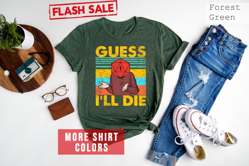 May include: A forest green t-shirt with a vintage-style graphic of a person with a dice for a head. The text on the shirt reads "Guess I'll Die".