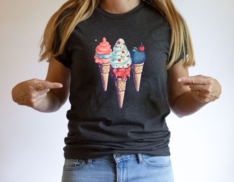 May include: A dark gray t-shirt with a graphic of three ice cream cones. The cones are topped with pink, blue, and purple ice cream and have a cherry, sprinkles, and a swirl design.