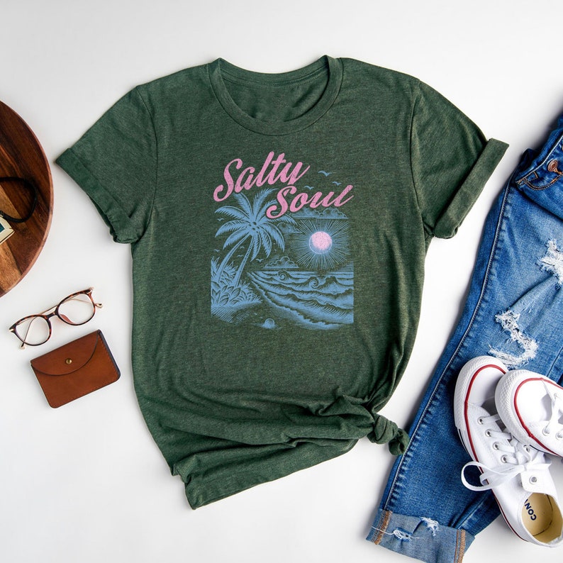 May include: A green t-shirt featuring a palm tree and ocean wave graphic. The text "Salty Soul" is printed in pink on the shirt.