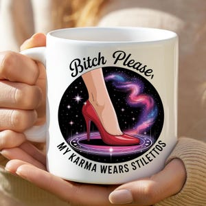 Op de afbeelding: Witte keramische mok met een afbeelding van een rode stilettohak in een zwarte cirkel met een kosmische achtergrond. De tekst "Bitch Please, My Karma Wears Stilettos" is rond de cirkel gedrukt.