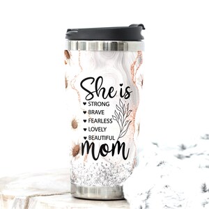 May include: Stainless steel travel mug with a black lid. The mug features a white marble design with gold and silver accents, and small sunflower illustrations. Text on the mug reads "She is STRONG, BRAVE, FEARLESS, LOVELY, BEAUTIFUL mom."