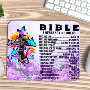 May include: A purple and white mouse pad with a cross and butterflies. The text "BIBLE EMERGENCY NUMBERS" is printed on the mouse pad with a list of Bible verses for different feelings.