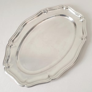 Peut inclure: Un plateau de service ovale argenté avec un bord festonné. Le plateau a une surface réfléchissante et une bordure décorative. Ce plateau vintage est adapté pour servir des aliments ou exposer des objets.