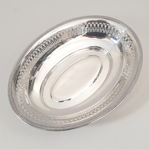 Peut inclure: Un plat de service ovale en argent poli. Le plat présente une bordure ajourée décorative et une surface lisse et réfléchissante. Le bord est orné d'un bord perlé. Cette pièce élégante est idéale pour servir des aliments.