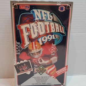 Puede incluir: Una caja de cartas de intercambio de fútbol americano NFL Upper Deck de 1991. La caja presenta un diseño rojo, blanco y azul con un jugador de fútbol americano con un uniforme rojo y dorado. La caja dice "¡Edición Premier!" y "Encuentra a Montana".