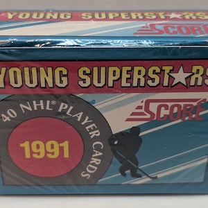 May include: A blue and white box with the text "Young Superstars" and "Score" on it. The box also has a red circle with the number "1991" in yellow text. The box is for a set of 40 NHL player cards.