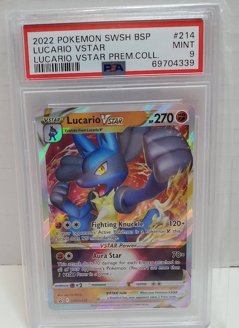Może przedstawiać: Karta Pok&eacute;mon Lucario VSTAR z zestawu Miecz i Tarcza. Karta jest holograficzna z ilustracją niebieskiego i czarnego Lucario. Karta ma 270 PW i posiada dwa ataki: Walczący Pięść i Gwiezdna Aura. Karta jest w idealnym stanie i ma ocenę PSA 9.