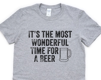 May include: A heather gray t-shirt with the phrase "IT'S THE MOST WONDERFUL TIME FOR A BEER" in black, along with a black line drawing of a beer mug. The shirt is made of a soft material.