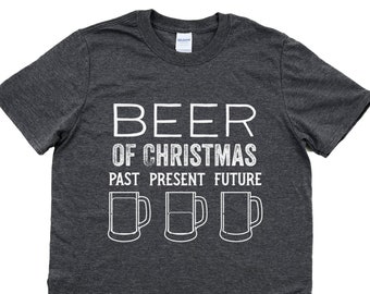 May include: A dark heather grey t-shirt with a white graphic that says "Beer of Christmas Past Present Future" with three beer mugs underneath.