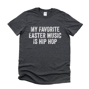 May include: Dark grey t-shirt with white text that reads "My favorite Easter music is hip hop".