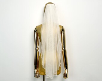May include: A white tulle bridal veil with a single layer and a scalloped edge. The veil is displayed on a gold mannequin.