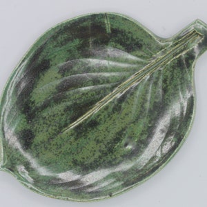 May include: A green ceramic leaf-shaped dish with a textured surface.