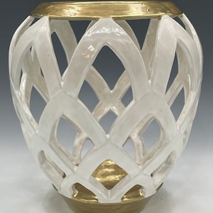 May include: White ceramic vase with a gold rim and base. The vase has a geometric, lattice-like design.