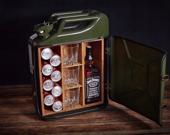 Puede incluir: Un bar de metal verde en forma de bidón de gasolina con una puerta con bisagras. El gabinete tiene un interior de madera con estantes para guardar botellas, vasos y latas. El gabinete está abierto y muestra una botella de whisky Jack Daniel's, vasos y latas de refresco.