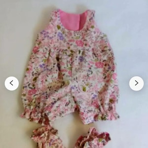 May include: A pink and white floral baby onesie with matching booties. The onesie has a sleeveless design and a ruffled hem. The booties are made of the same fabric as the onesie.