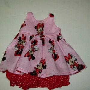 May include: A pink and red sleeveless dress with a Minnie Mouse print and a red and white polka dot diaper cover.