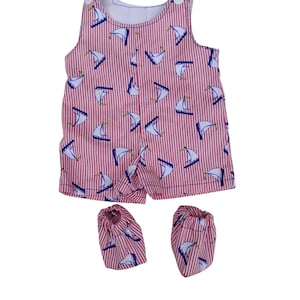May include: A red and white striped baby romper and matching booties. The romper features a pattern of white sailboats with blue accents. The outfit is sleeveless with a round neckline and button closures on the shoulders.