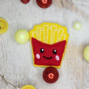 May include: A felt applique of a cartoon french fry container with a smiling face. The container is red with yellow french fries inside. The applique is surrounded by small yellow and red decorative balls and smiley faces.
