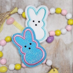 May include: Two felt Easter bunny shapes, one blue with pink trim and glitter, the other white with blue trim.
