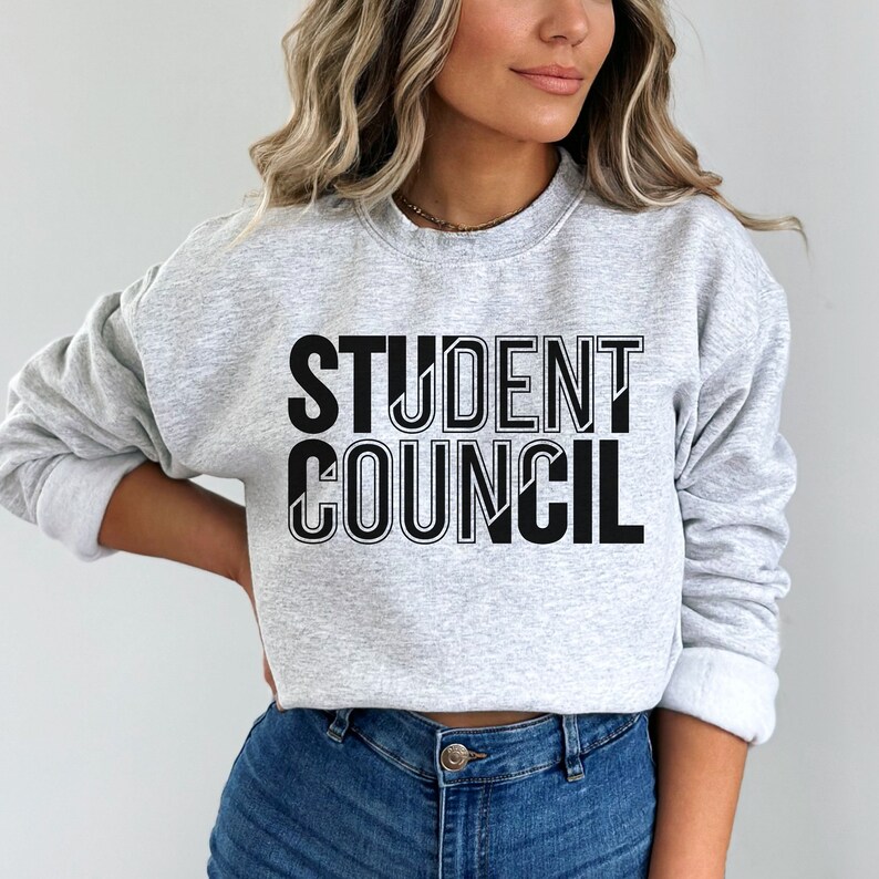 Pu&ograve; includere: Una felpa grigia con la scritta "STUDENT COUNCIL" stampata in nero sul davanti.