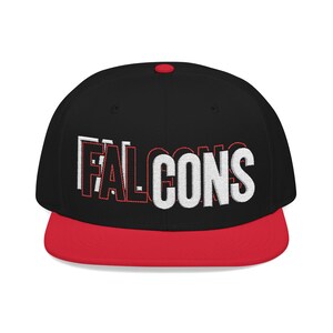 Könnte beinhalten: Eine schwarze Snapback-Kappe mit rotem Schirm und einem roten Knopf an der Oberseite. Auf der Vorderseite ist das Wort FALCONS in Weiß mit roter Umrandung gestickt, unterlegt mit einem weißen Schatteneffekt für eine markante, dreidimensionale Optik.