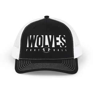 Puede incluir: Una gorra de camionero en blanco y negro con un panel frontal negro que muestra el texto blanco WOLVES FOOTBALL y un gráfico de un balón de fútbol americano en el centro. La gorra tiene una malla trasera blanca y visera negra con costuras.