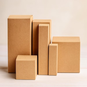 May include: A collection of various sized, brown cardboard boxes. The boxes are rectangular and square, with different heights and widths. The boxes are arranged in a group, suggesting they are for packaging or storage.