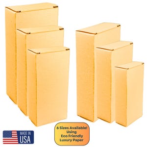 May include: Six different sizes of cardboard boxes, all made from eco-friendly luxury paper. The boxes are stacked in order of size, with the largest box at the bottom and the smallest box at the top. The boxes are all a light brown color.